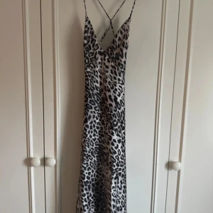 Leopardmönstrad klänning från Zara - Snygg leopardmönstrad klänning från Zara med tunna axelband och djup v-ringning. Klänningen har en lång siluett och dragkedja i ryggen  för enkel påklädning. Perfekt för en trendig look!
