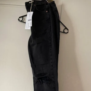 Gina Tricot- petite jeans - Snygga svarta jeans med slitningar på knäet. Svarta jeans i storlek 32. Helt nya med lappen kvar