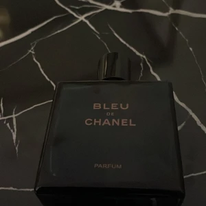 Bleu de Chanel Parfum - Säljer en elegant och tidlös Bleu de Chanel Parfum. Flaskan är mörkblå och fyrkantig med en stilren design. Den har en svart kork med Chanels ikoniska logotyp på toppen. Perfekt för den som vill ha en sofistikerad doft. Den har ca 60ml kvar, köpt för 2500kr