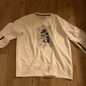 Vit sweatshirt från Nike - Säljer en vit sweatshirt från Nike med ett coolt Air Max-tryck på framsidan. Tröjan har långa ärmar och en rund halsringning. Perfekt för en avslappnad stil.