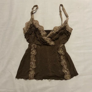 Vintage brun spetstopp - Söt spetstopp med lite babydoll-aktig passform. Figurnära runt bröstet och blir sedan mer ”flowy” längre ner. Köpt second hand men finns nästan inga tecken på användning.