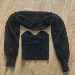 Svart ribbad tubtopp med bolerotopp - Snygg svart ribbad tubtopp med matchande bolerotopp. Tubtoppen har en hjärtformad urringning och bolerotoppen har långa ärmar.