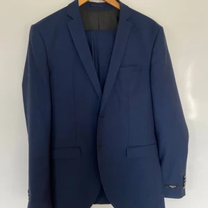 Blå kostym från Jack & Jones - Snygg mörkblå kostym från Jack & Jones i super slim passform, passar den som har m i storlek. Kavajen har klassiska slag och knappar vid ärmsluten. Byxorna har en stilren design med knappstängning. Perfekt för en elegant look. Använd fåtal gånger bara att höra av sig vid intresse mvh