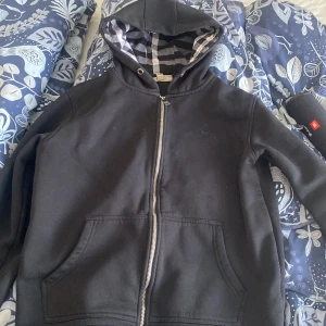 Svart burberry hoodie - Tja boys! Säljer nu en svart burberry hoodie i väldigt bra skick! Den ända defekten är att dragkedjan är lite trög men den funkar fortfarande galant! Storlek L men skulle passa M också då jag har M och kan använda den! Vid fler frågor skicka iväg ett meddelande!