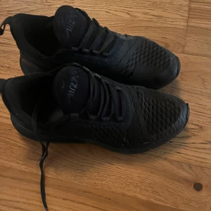 Svarta Nike Air Max sneakers - Säljer ett par svarta Nike Air Max sneakers med snörning och en luftig design. Skorna har en synlig Air Max-dämpning i hälen för extra komfort. Perfekta för både träning och vardag.