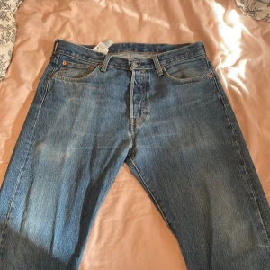 Blå jeans från Levis - Säljer ett par klassiska blå jeans från Levis. De har en rak passform med fem fickor och en knappgylf. Perfekta för en avslappnad stil. 