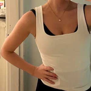 Vitt linne från Hope & Ivy - Säljer en stilren vit linnetopp från Hope & Ivy. Toppen är ärmlös med en fyrkantig urringning och har en tight passform. Perfekt för varma sommardagar eller som ett basplagg i garderoben. Passar även som träningslinne till yoga och pilates.