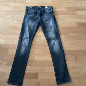 Svarta slim jeans från Jack & Jones - Säljer ett par svarta slim fit jeans från Jack & Jones, modell Glenn. Jeansen har slitna detaljer på benen och klassisk femficksdesign. Hyfsat sällsynta, dom är i perfekt skick till ett sjukt bra pris!🙌