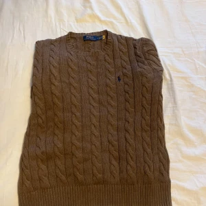 Brun kabelstickad tröja från Polo Ralph Lauren - Tja! Säljer en helt ny och oanvänd ralphlauren tröja! Den har ej kommit till användning för mig då den inte sitter så bra på mig tyvärr. Köpte denna för 1200kr men vill helst bara få iväg den så säljer den för 500kr! Pris är diskutabelt!