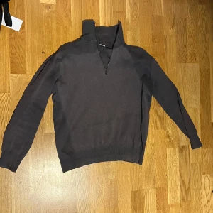 Mörkgrå stickad tröja med dragkedja från Zara - Mörkgrå stickad tröja från Zara med halv dragkedja och hög krage. Tröjan har lång ärm och ribbade muddar vid ärmslut och nederkant. Perfekt för lager-på-lager och enkel att matcha med olika outfits.  —— Använd ett flertal gånger tidigare, men inte på över ett år nu eftersom den är för liten på mig. Normal i storleken och inga fel på den.