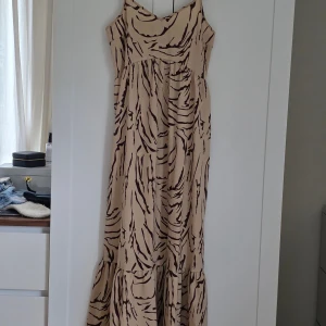 Beige långklänning med zebramönster från PIECES - Säljer en beige långklänning från PIECES med brunt zebramönster och smala axelband. Klänningen har en luftig passform och är perfekt för varma dagar. Tillverkad i ett mjukt, lätt material som känns skönt mot huden. Använd 1 gång.  Finns ute på flera sidor. 