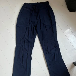 Mörkblå linnebyxor  - Säljer ett par mörkblå linnebyxor med resår i midjan. Byxorna har raka ben och en avslappnad passform, perfekta för varmare dagar. Materialet är svalt och luftigt. Köpte på marknad i Spanien så har ingen lapp eller märke. Sitter jättebra på men har blivit lite för små för mig så säljer. Bilden på är på ett par svarta likadana, men dessa är i mörkblå. Skriv för fler bilder💙