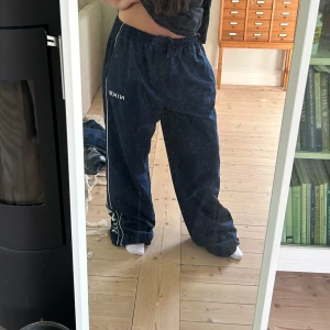 Blå vida mjukisbyxor från Nike - Säljer ett par blå mjukisbyxor från Nike med vita ränder längs sidorna och logga på låret. Byxorna har snöre i midjan vilket gör att dom passa många eftersom man kan spänna in och spänna ut 