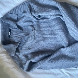 Grå ribbad stickad polotröja från Gina tricot  - Säljer en grå stickad polotröja från Gina tricot. Tröjan är ribbad och har långa ärmar samt en klassisk polokrage. Perfekt för kyligare dagar och enkel att matcha med olika outfits.