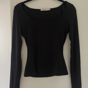 Svart ribbad långärmad topp  - En svart långärmad topp från NA-KD med ribbad struktur och rundad urringning. Perfekt basplagg som är enkel att matcha till olika outfits.