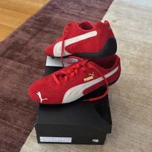 Puma Speedcats OG - Säljer ett par röda Puma sneakers i mocka med vita detaljer och svart sula. Skorna har klassisk snörning och en sportig look med Pumas logga i guld på sidan. Dessa användes på Fashionweek i Paris under modevisningen för Ravenreview så deras special skosnören och en fluga följer med. Bara använda på catwalken.