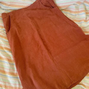 Rostbrun linnekjol  - Säljer en rostbrun kjol i linne. Kjolen har en rak passform och är knälång med diskreta fickor i sidorna. Perfekt för dig som gillar en enkel och stilren look med naturliga material.