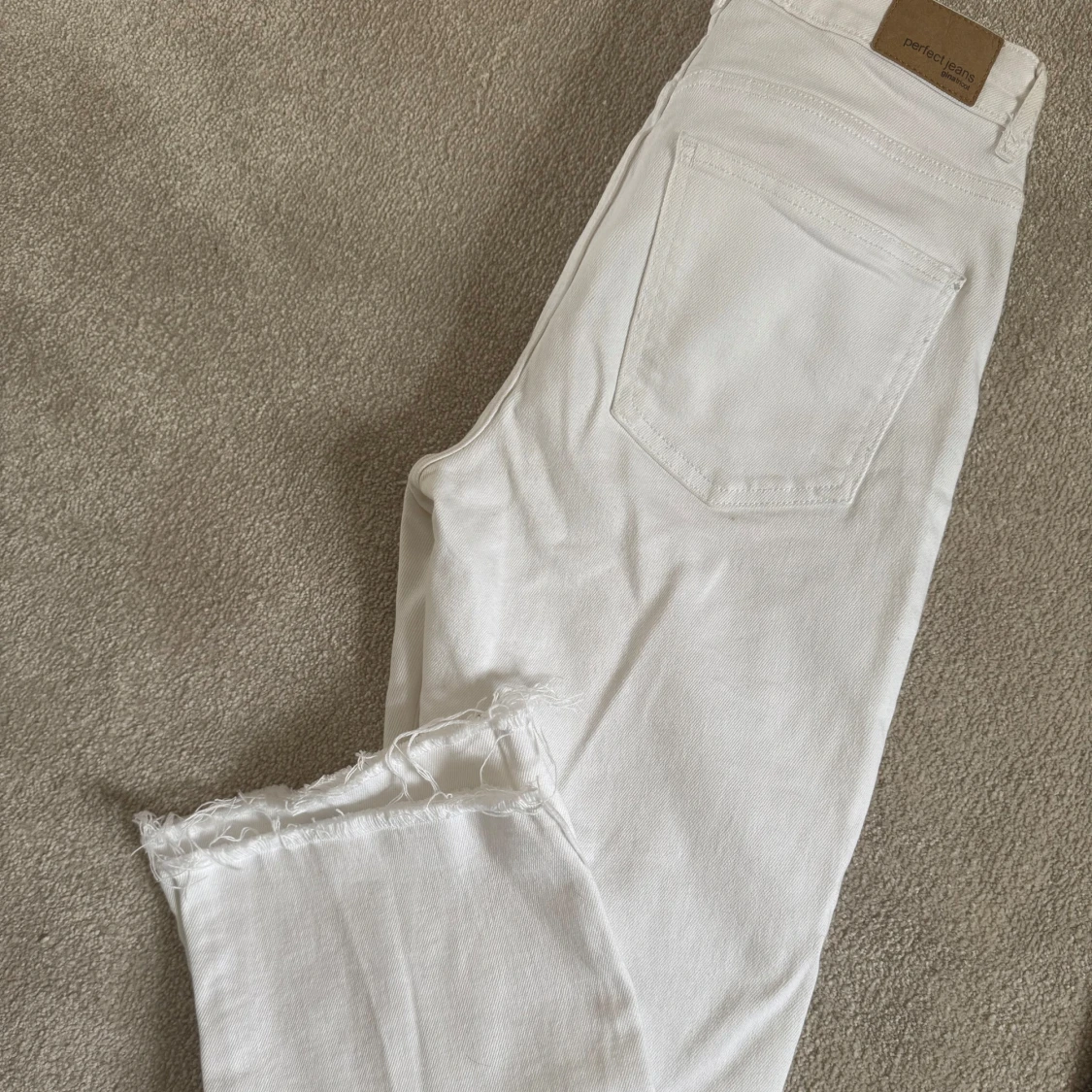 Vita jeans med råa benslut