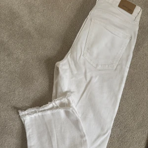 Vita jeans med råa benslut - Säljer ett par vita jeans från Ginatricot med raka ben och råa, fransiga benslut. Klassisk femficksmodell och normal passform. Perfekta för en fräsch och stilren look. Medelhög midja. Använda men fint skick! strl 34 men passar strl 36 också då dom är stretchiga och töjs. 