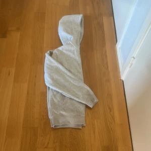 Ljusgrå hoodie med dragkedja från Weekday - Säljer en ljusgrå hoodie från Weekday i storlek S. Tröjan har dragkedja framtill, huva och två fickor. Perfekt för en avslappnad stil och enkel att matcha med det mesta.
