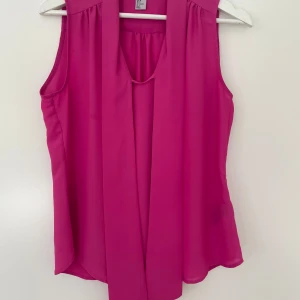 Rosa blus - Rosa blus med två tyger framtill som man kan görs en rosett av 🎀. I väldigt fint skick. 