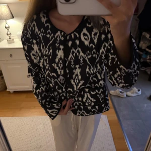 Svartvit mönstrad overshirt - Säljer en svartvit overshirt med unikt rutigt mönster och rund halsringning. Jackan har knappar framtill och raka, långa ärmar. Perfekt för dig som vill sticka ut med en cool och trendig look.