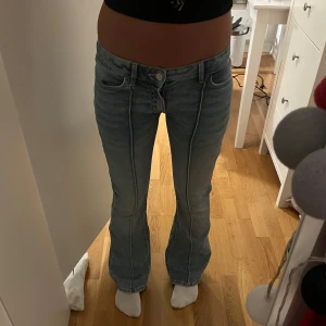 Ljusblå bootcut jeans med söm - Säljer ett par ljusblå jeans med markerad söm längs benen och snygga fickor bak med knappdetalj. Modellen är bootcut med lite utsvängda ben och mid midja. Perfekta för dig som vill ha något som sticker ut lite extra. Älskar dem så mycket men kommer inte till andvöndning❤️❤️ny pris:750kr