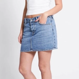 Blå jeanskjol med klassisk passform - Snygg blå jeanskjol i klassisk modell med fem fickor, bälteshällor och knapp- samt dragkedjestängning framtill. Kjolen är kort och har en rak passform som ger en avslappnad vibe. Perfekt att matcha med en crop top eller hoodie för en cool look.