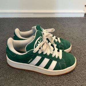 Adidas Campus gröna sneakers  - Gröna Adidas Campus sneakers i mocka med klassiska vita ränder och vit sula. Trendiga och perfekta till vardags!