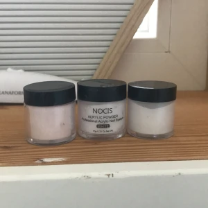 NOCIS akrylpulver för naglar - Tre burkar NOCIS akrylpulver för professionellt akrylnagelsystem. En burk är märkt 'WHITE', de andra är i ljusa, neutrala nyanser. Perfekt för att bygga och forma snygga naglar hemma. Kommer i genomskinliga plastburkar med svart lock. En är lite använd resten är igen använda