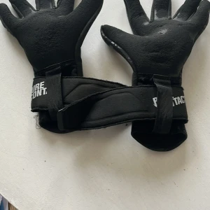 Svarta målvaktshandskar Pure Contact - Svarta målvaktshandskar från Pure Contact med greppig yta och breda kardborreband runt handleden. Perfekta för fotbollsmålvakter som vill ha bra grepp och stöd. Snygg, sportig design med tryckt logga på bandet.