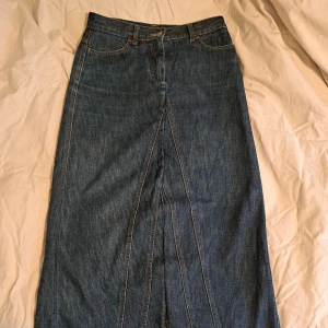 Lång jeanskjol - Lång jeanskjol i klassisk blå jeans. Kjolen har fickor både fram och bak, bälteshällor och stängs med knapp och dragkedja. Kjolen är lite kort för mig som är 172. Om ni vill se fler bilder eller har en fråga är det bara att höra av sig <3