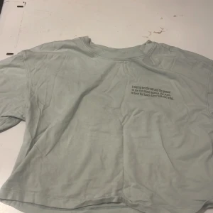 Ljusblå croppad t-shirt med text - Ljusblå croppad t-shirt med kort ärm och tryckt text på bröstet. T-shirten har en avslappnad passform och är tillverkad i mjuk bomull. Perfekt för en chill och enkel stil.