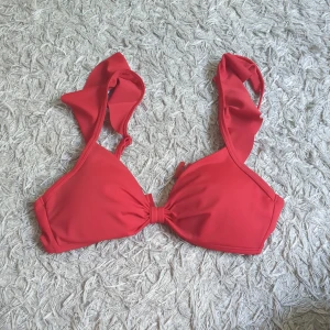 Röd bikiniöverdel - Snygg röd bikiniöverdel med volangdetaljer på axelbanden och knyt framtill. Bikinin har justerbara axelband och stängs med spänne i ryggen. Perfekt för sommardagar vid stranden eller poolen. Har fortfarande prislappen kvar (249 så lägsta jag vill gå är 220 typ) ☺️