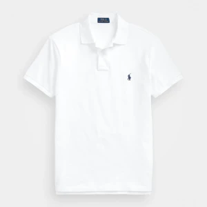 Vit pikétröja från Polo Ralph Lauren - Klassisk vit pikétröja från Polo Ralph Lauren med korta ärmar och broderad marinblå logga på bröstet. Tröjan har krage och knäppning framtill. Perfekt för en clean och stilren look. (Kvitto finns)