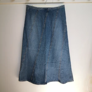 Lång blå Denim kjol  - Lång blå jeanskjol från Bona Parte i 100% bomull. Kjolen har en klassisk A-linjeform med dekorativa sömmar på diagonalen, med dragkedja i midjan. Kjolen är 86 cm lång. 