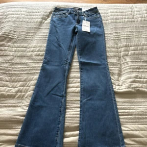 Blå bootcut jeans från ONLY, PRIS DIKUTERAS!!! - Snygga blå jeans från ONLY med klassisk femficksmodell och bootcut-ben. Jeansen har normalhög midja och är tillverkade i mjukt denimtyg med lite stretch för extra komfort. Perfekta för dig som gillar retrovibbar och vill ha ett par jeans som sticker ut.