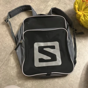 Grå ryggsäck med vadderade axelband - Säljer en stilren grå ryggsäck med vadderade axelband och flera fack. Väskan har dragkedja upptill och ett stort huvudfack med innerficka, perfekt för skola eller vardag. Tillverkad i slitstark polyester och har justerbara remmar för bästa passform.