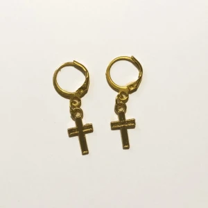 Guldiga örhängen med kors - Snygga örhängen i guldton med hängande kors. Klassisk design med små ringar och enkla kors som ger en cool och stilren vibe. Perfekta för dig som gillar statement-accessoarer med en touch av edge.
