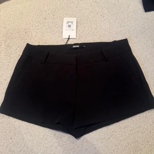 Svarta shorts från BikBok - Klassiska svarta shorts från BikBok med midwaist passform. De har bälteshällor, diskreta fickor bak och en stilren look som passar till många olika outfits. Materialet känns mjukt och har en lätt stretch för extra komfort. Kostym shorts 