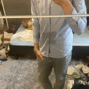 Ralph Lauren skjorta - Säljer en klassisk ljusblå skjorta från Ralph Lauren i storlek M. Skjortan har lång ärm, knappar framtill och den ikoniska broderade polospelaren på bröstet. Tillverkad i bomull och passar perfekt till jeans eller chinos.