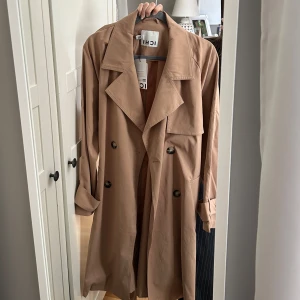 Beige trenchcoat från ICHI med bälte - Snygg beige trenchcoat från ICHI med klassisk krage. aldrig använts endast prövat!! Original pris 1399kr. Om du har frågor, tvivla inte att skriva 