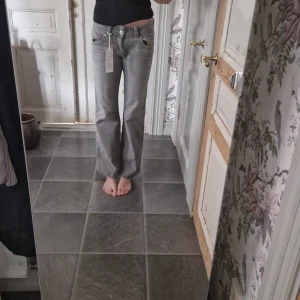 Gråa jeans från gina tricot - Säljer ett par gråa jeans från Gina Tricot i storlek 36. De har en rak och lite vidare passform med snygga detaljer som dubbla knappar och fickor med lock bak. Jeansen är i klassisk denim och har en cool, avslappnad vibe. Mycket fint skick, prislappen är fortfarande på! 
