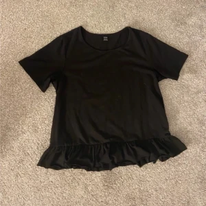 Svart-shirt volang - Fin T-shirt med volanger längst ner. XS/S