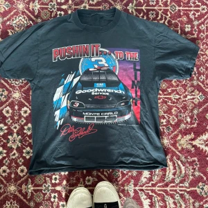 Svart NASCAR t-shirt Dale Earnhardt - Cool svart t-shirt med stort NASCAR-tryck fram och bak, featuring Dale Earnhardt och Monte Carlo-bil. Feta färger i blått, rött och vitt, klassisk racing t-shirt