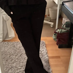 Svarta lågmidjade kostymbyxor - Snygga svarta lågmidjade kostymbyxor med raka ben och dekorativa bakfickor