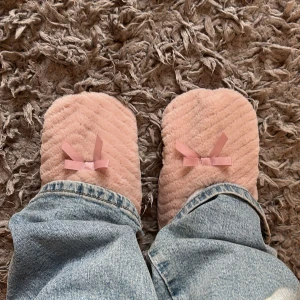Rosa fluffiga ballerinatofflor med rosett - Supermjuka och mysiga ballerinatofflor i ljusrosa plysch från Mywear. De har en söt liten rosett framtill och ett diskret mönster i tyget. Perfekta att glida runt i hemma när du vill ha det extra bekvämt.
