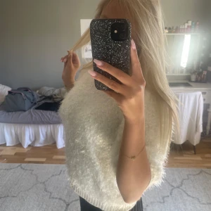 Vit fluffig stickad tröja - Supermjuk och fluffig vit stickad tröja med korta ärmar och rund hals. Tröjan har en lätt glittrig känsla i materialet och är perfekt för dig som gillar en cozy och trendig vibe. Passar snyggt till både jeans och kjol.