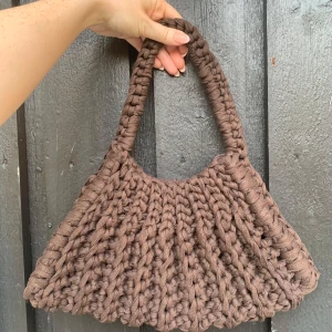 Brun virkad axelväska - Säljer en brun virkad axelväska. Väskan har ett grovt och rejält handtag som gör den enkel att bära. Perfekt för dig som gillar unika accessoarer med en cozy vibe.