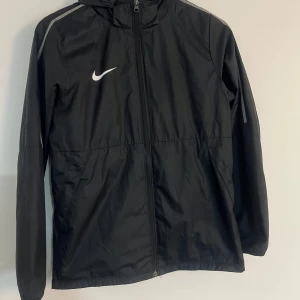 NIKE REGNJACKA - Säljer nu min Nike regnjacka. Tunn och väldigt skön och luftig, känns ej som en typisk regnjacka. Passar perfekt att lira fotboll i. Skulle säga den passar från 12-15 år 